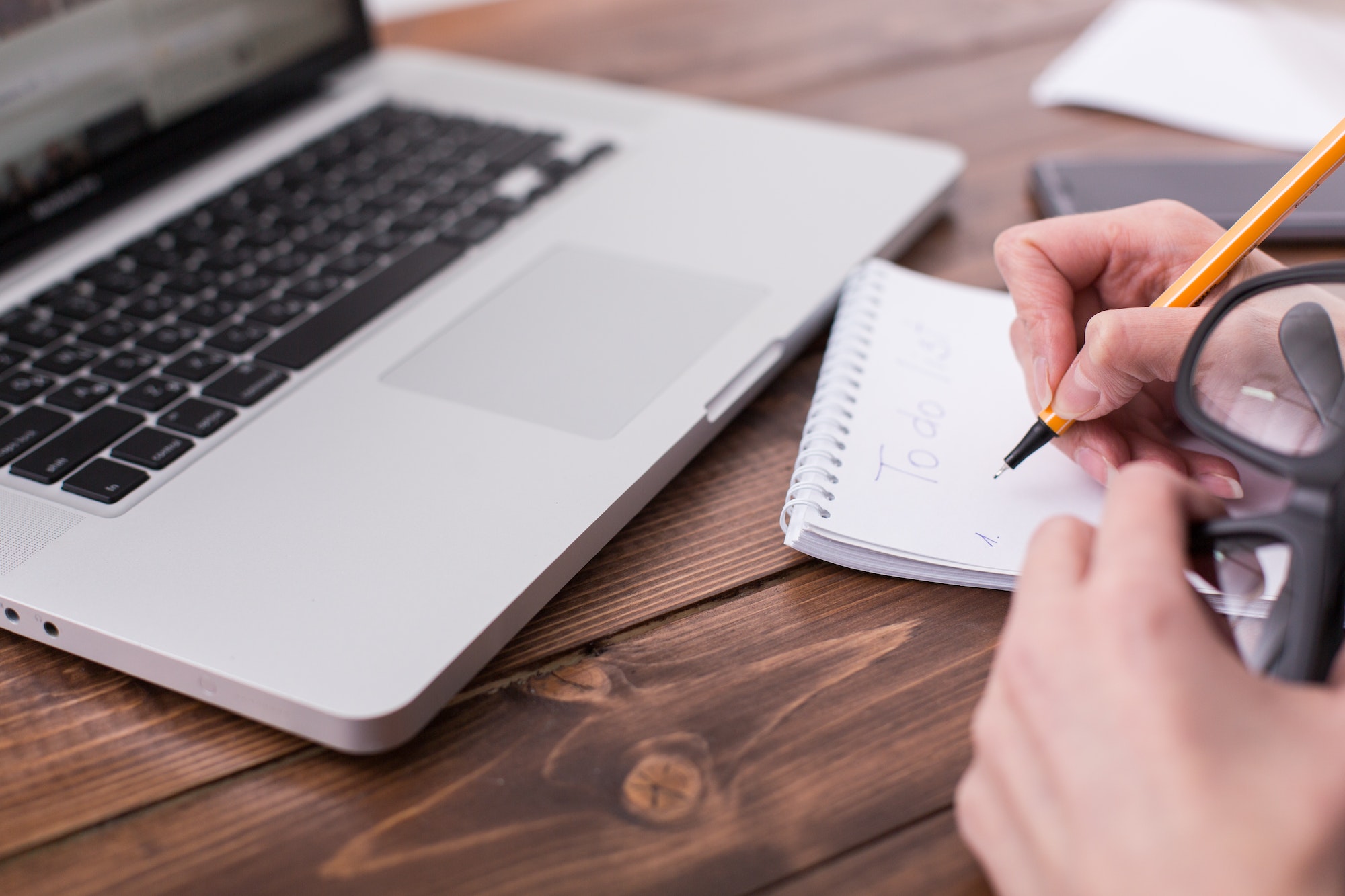 Young woman with laptop writes a to-do list in a notebook. Businesswoman writing a to do list while